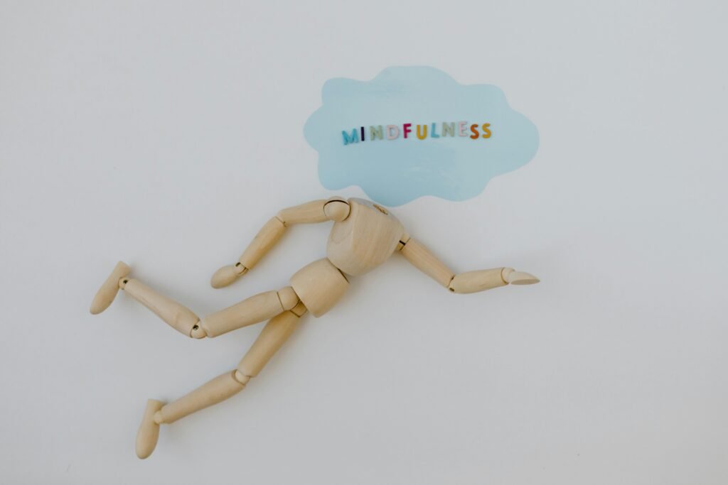 Wooden mannequin with speech bubble highlighting mindfulness concept on white background.